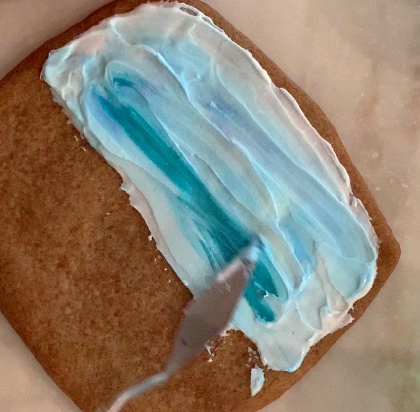 Spread and blend Royal Icing on the top half of the cookie with a spatula to make the sky.
